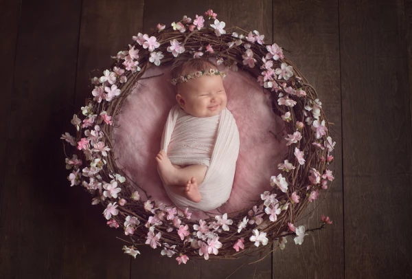 As I am based in the Washington, D.C metropolitan area in the United States, which is famous for, among other things, the pink cherry blossom trees that bloom around the national monuments in the spring, this little sweetheart's mom and I couldn't resist the idea of a cherry blossom wreath for her session. As this little girl was about 6 weeks old at the time, we thought that perhaps she might be awake and alert for the photos but, as soon as I wrapped her up, she fell right asleep and started flashing me beautiful, gigantic smiles like the one you see in this image!