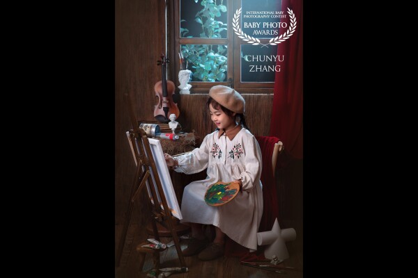 A quiet little girl in a white and elegant dress sits in front of the drawing board, painting mysterious paintings, and the quiet scenery outside the window contrasts with each other.