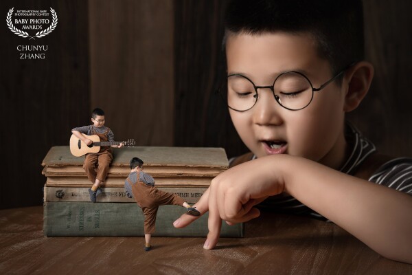 This little boy likes to play the guitar and also likes taekwondo. Look, he is fighting with his own fingers, and the other one is watching while playing the guitar.