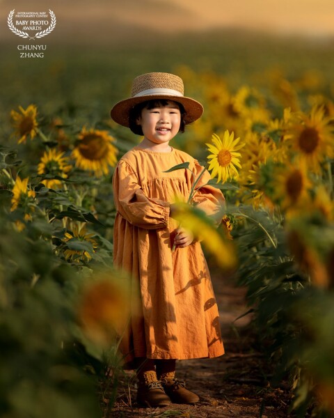 In the sunset, I took my daughter to a field of sunflower flowers. The color of  sunflowers and the color of the sun, and her yellow clothes are also very matching, then,  I took this perfect picture.