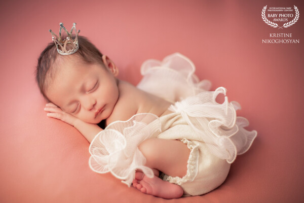 Cradled in the hush of rosy light, this little angel rests in a whisper of ruffles, crowned with the...