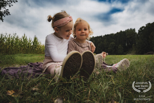 This photograph captures a quiet moment between two cousins during a family photoshoot. Sitting clos...