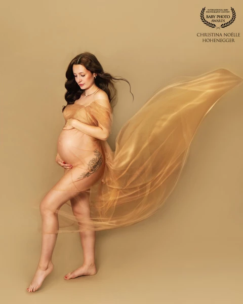 Wrapped in flowing, translucent fabric, the mother-to-be radiates strength, serenity, and timeless f...