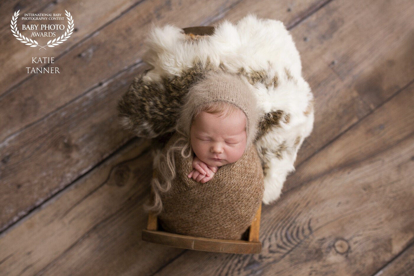 Everette from Dawson creek British Columbia Canada, wearing an angora bonnet and wrap tucked into a handmade wooden newborn bed.