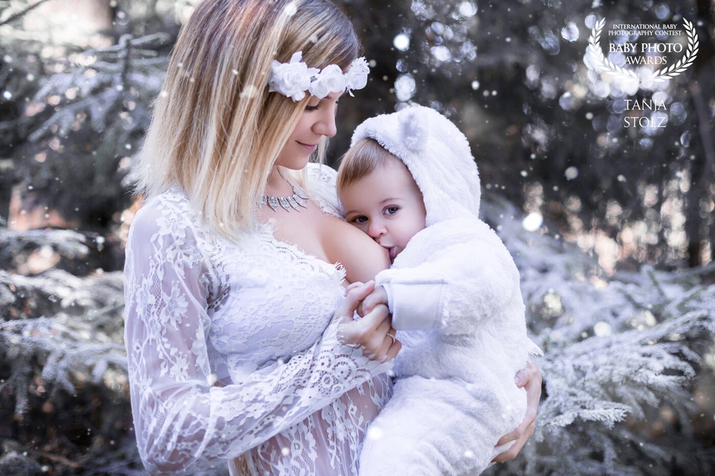 As Austria's leading breastfeeding photographer, I always look out for THIS very special and magical moment between a loving mother and her child. I try to capture their most beautiful and intimate pose in gorgeous outfits and even more stunning surroundings. But for this winter-shot, we had to improvise a little bit. Because with no snow on our shooting-day, I had to use snow-spray to cover up some branches and add a few snowflakes in post-production. I'm pretty happy with the final outcome. This lovely picture turned out to become my very first cinemagraph too. Check out my Youtube channel to view all the magic! https://www.youtube.com/watch?v=VFNc72oFnoM<br />
