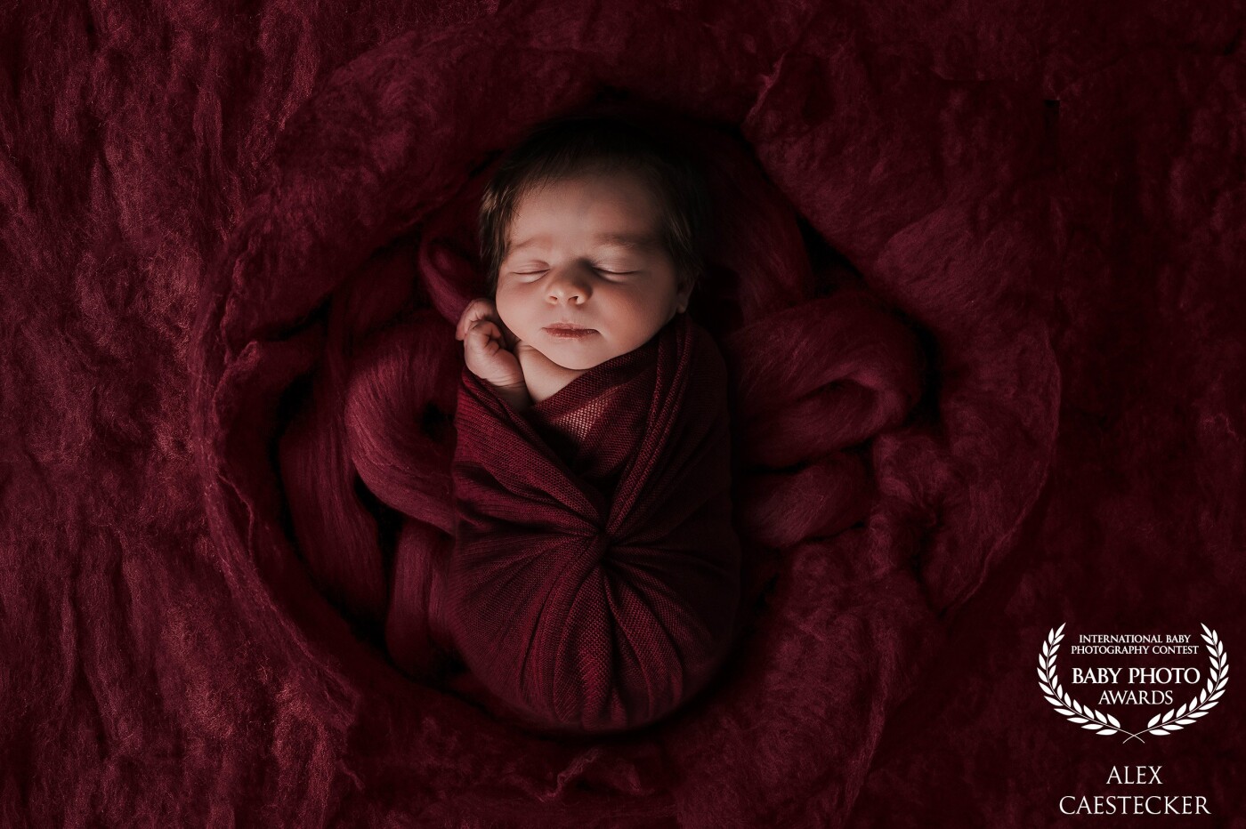 From the moment this little girl came to our studio, she was so relaxed and really enjoyed my hands while posing her. <br />
With this cute, completely relaxed face, we didn't want to create a typical soft pink newborn picture. We searched for a little mystery in the picture by using warm, red colors.