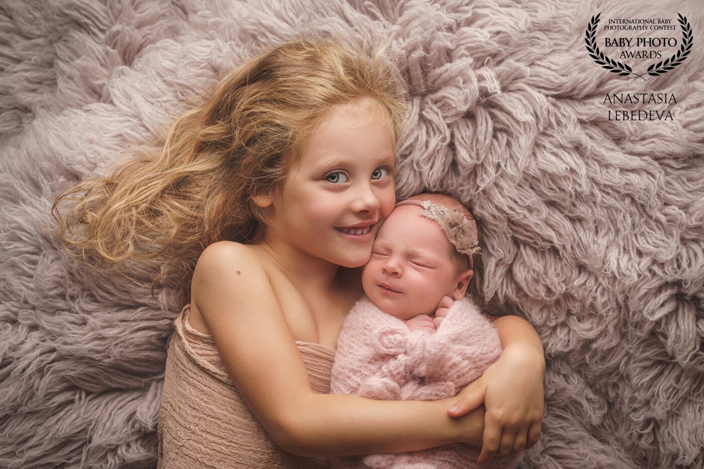 There are two lovely sisters in this photo.  The eldest is insanely happy with the appearance of a newborn sister, her eyes are filled with love and tenderness.  I really love this photo.