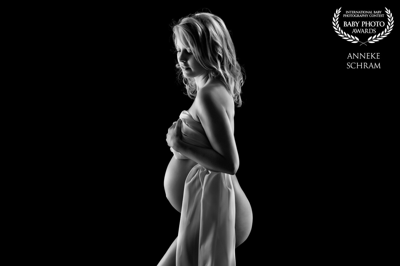 A very simple light setup of two gridded strip lights left and right of this beautiful mom-to-be.  This image was the best one in a series, as I really like the balance front/behind created by the fabric.