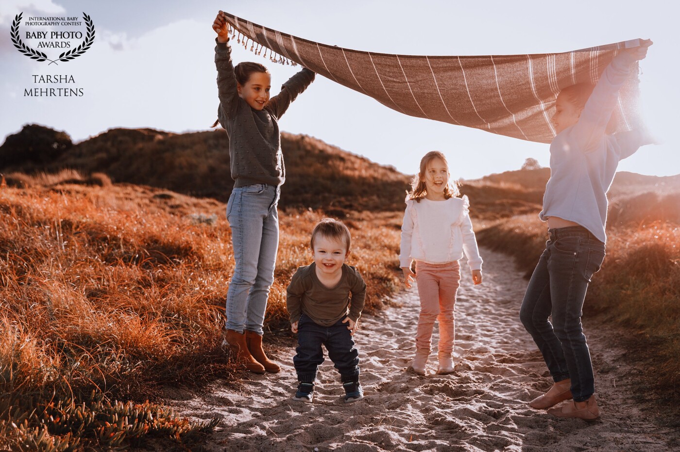 A gorgeous sunset session with these four children at Papamoa Beach, Bay of Plenty, New Zealand.  Lots of fun and laughter playing with the towel to get beautiful smiles.