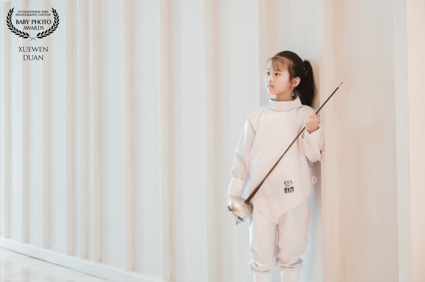 The fencing girl, Qiqi, 7, is a lively and lovely girl. She looks very beautiful after she wears fencing clothes. We took this picture in the corner of the hotel lobby.