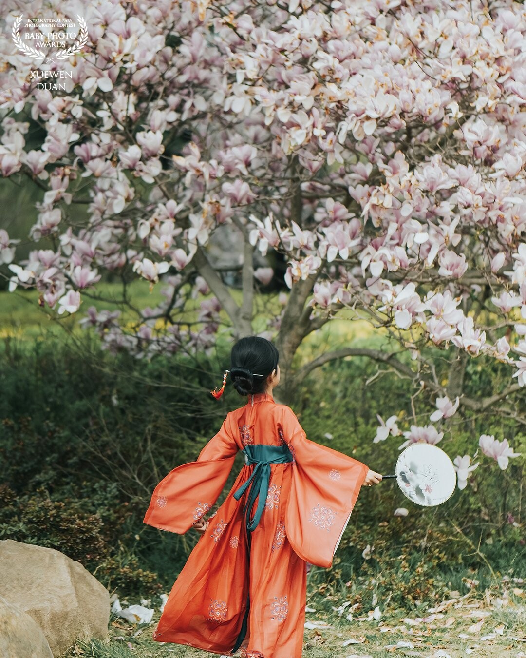 Walking in the park of Qingdao, I caught my favorite picture. A beautiful girl ran to the tree full of flowers in the spring breeze.