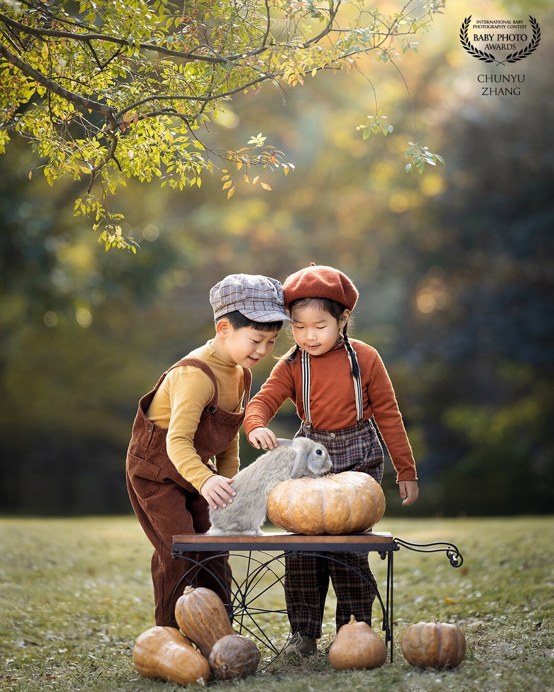 In autumn, the pumpkin harvest season has arrived. Two children came to the woods to play with the rabbits. They touched the little rabbit together, chatted together, and were super happy