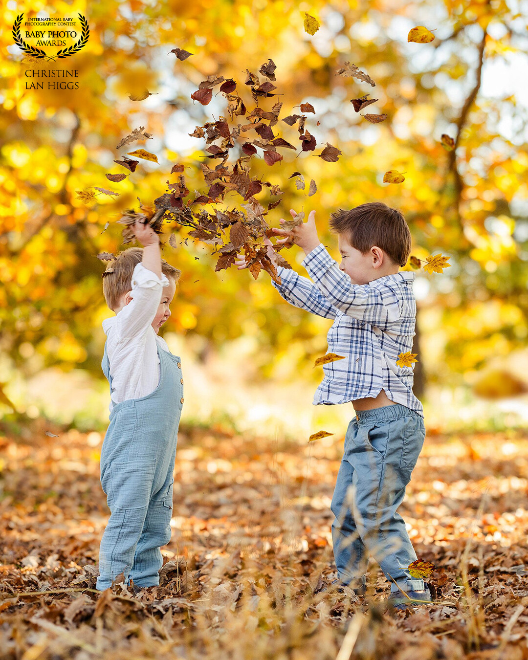 Boys gleefully tossing leaves, creating a lively burst of autumn joy.