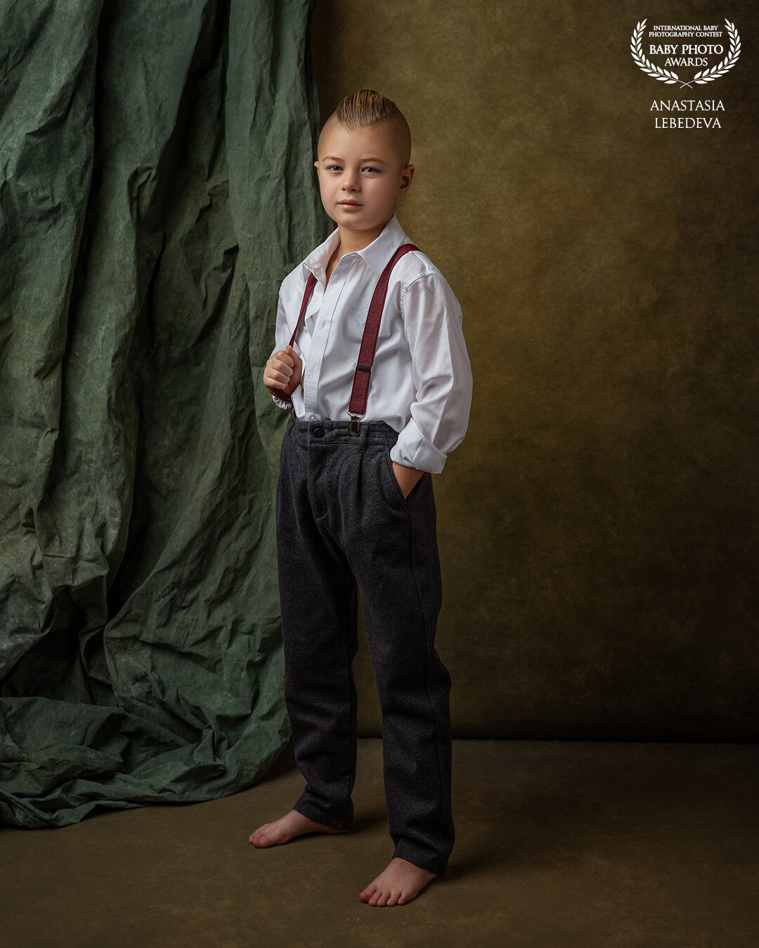 I am so happy to be here again. My model Fedor and I have created many images, and here is another image in front of your eyes. The boy is wearing a white shirt with a slightly unbuttoned collar, which adds a casual touch to the image. The red suspenders stand out gracefully against his dark trousers, and the stylish side parting in his hair gives him a serious, but at the same time playful look. With this photo, I wanted to show that every child has the potential for stylistic self-expression and a deep inner world. I hope this work will evoke warm feelings in you and remind you of the simple joys and uniqueness of youth.