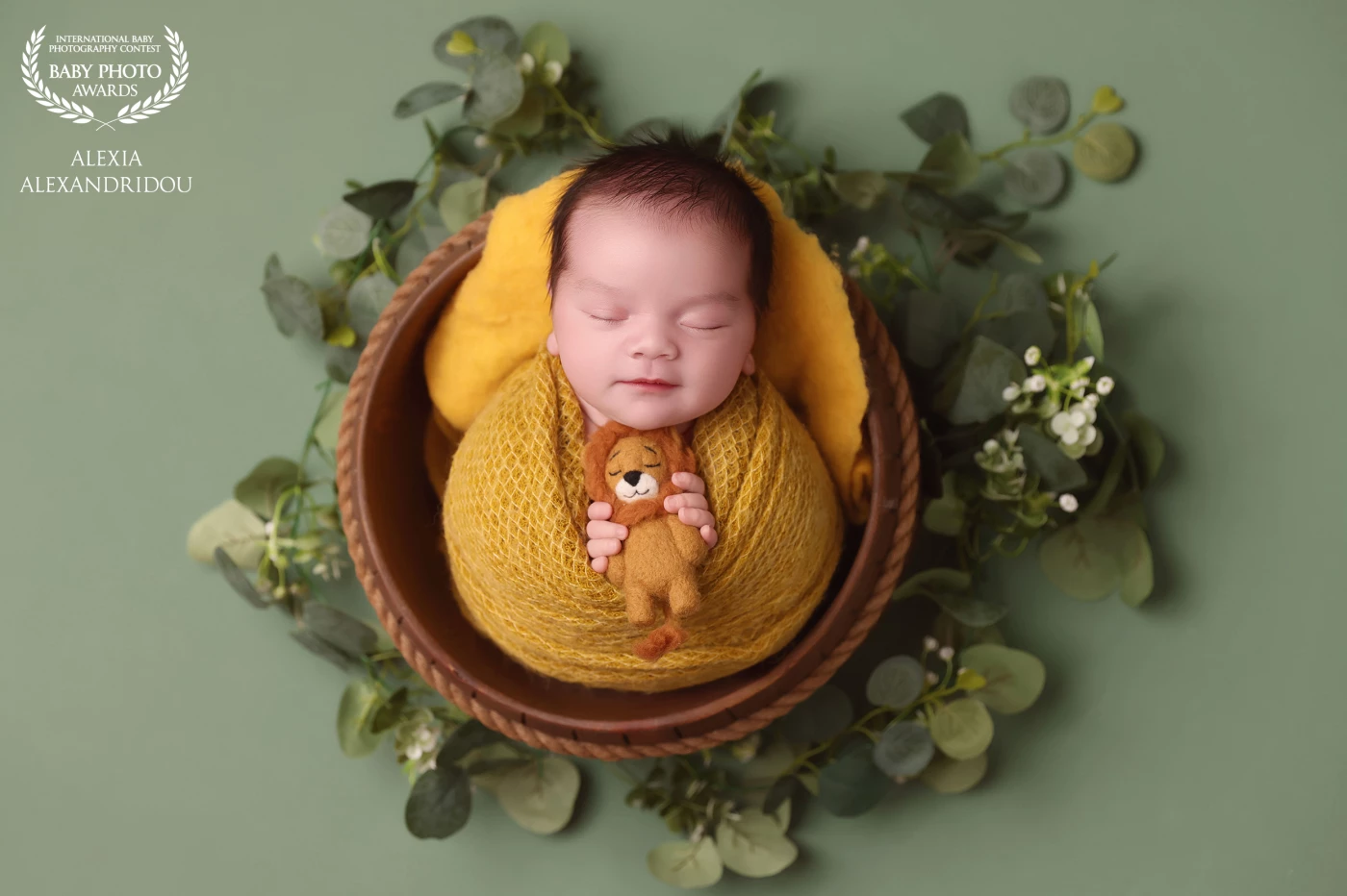 A peaceful newborn portrait, wrapped in warm yellow tones, surrounded by soft greenery and innocence.