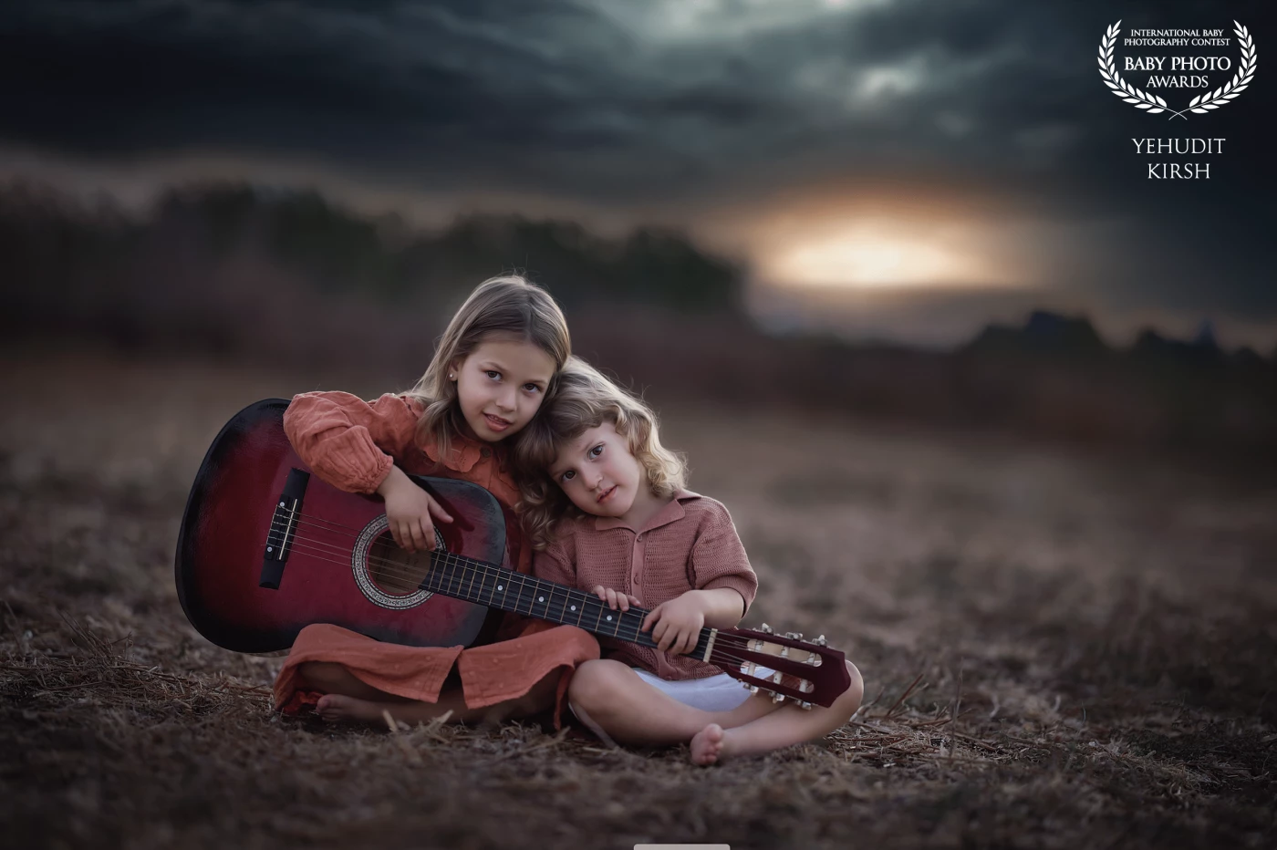 As darkness settles over the quiet landscape, a brother and sister sit side by side, sharing a single guitar. The faint light outlines their figures against the deep blue of evening, while soft chords echo gently through the still air — a serene moment of music, unity, and calm beneath the night sky.