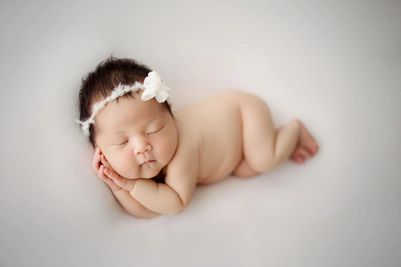 A classic newborn pose, nestled with tiny hands resting gently against their cheek. I wonder what be...