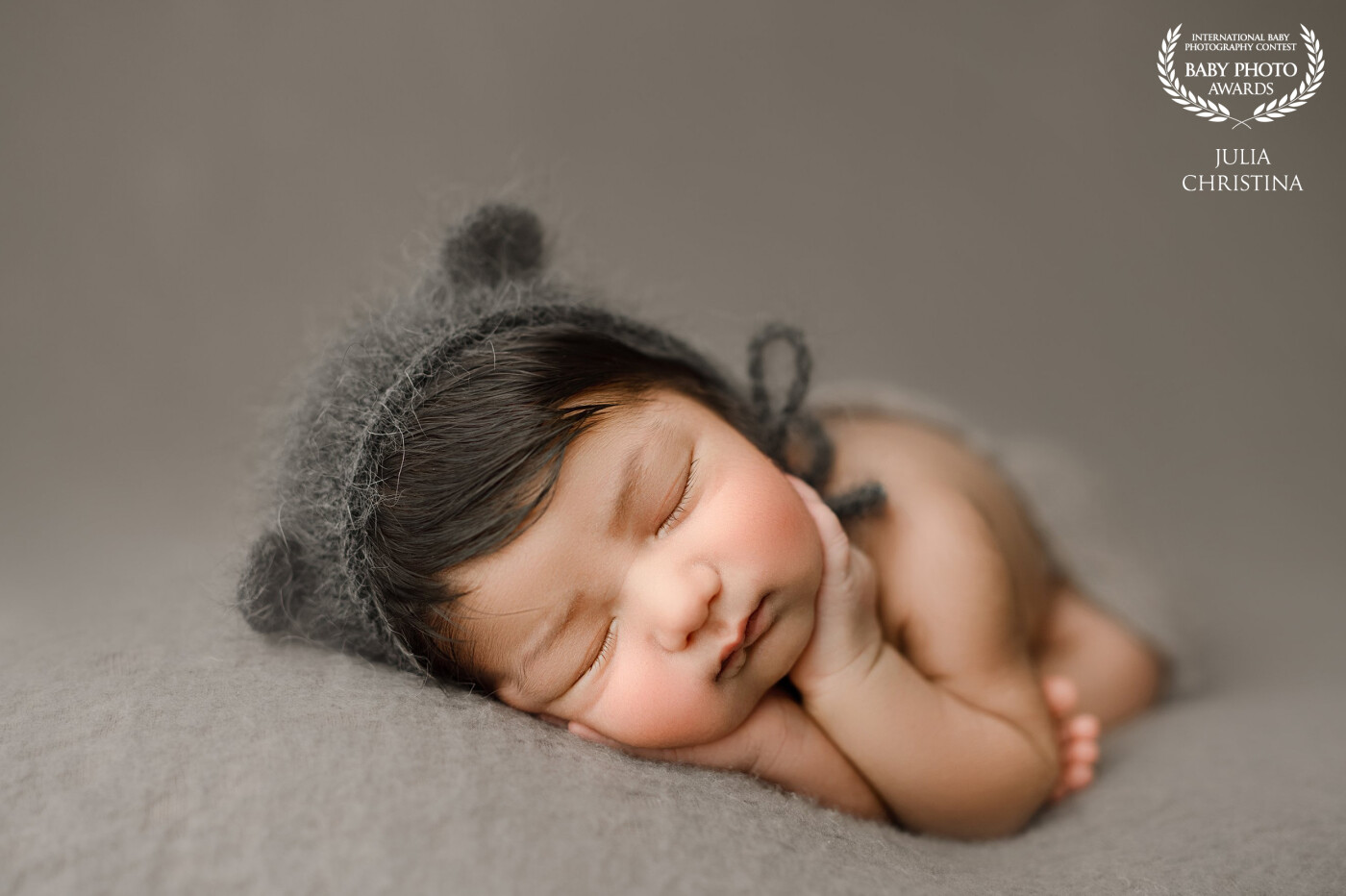 posed newborn baby in "timber pose" with grey bear bonnet on.