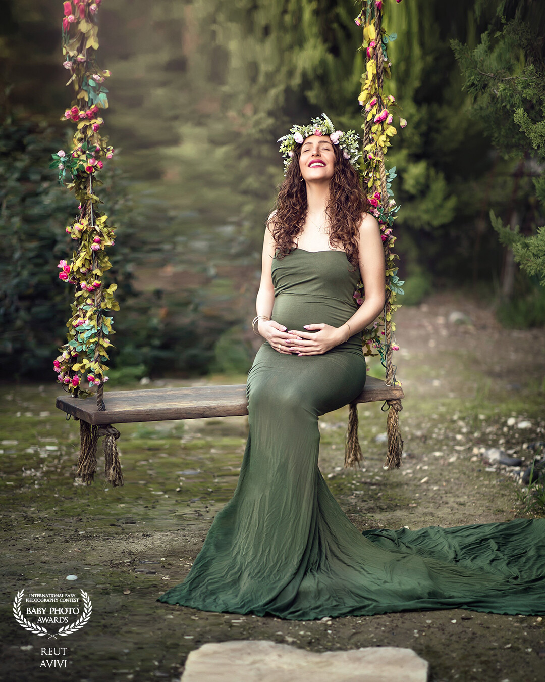 As she sat on the swing, the gentle breeze blew her face, revealing her glowing smile. The flowers adorned the swing, adding to the serenity of the moment. She rubbed her pregnant belly, feeling the life growing inside her, and whispered a prayer of gratitude. The green dress complemented the surrounding nature, making her stand out as the beautiful mother-to-be that she was.